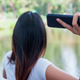 A woman raises her arm to throw her phone into a lake